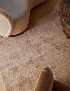 a close up of a rug on a wooden floor next to a chair and footstool