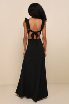 the back of a woman wearing a long black dress with a bow at the waist