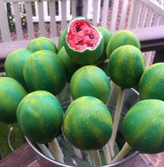 a metal bucket filled with green fruit on top of a wooden table