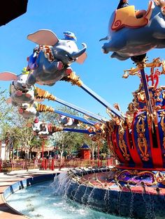 an amusement park with many rides and floats in the air, including elephants flying over water