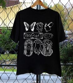 a t - shirt hanging on a chain link fence with words written in white ink