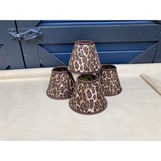 four leopard print lampshades sitting on top of a white table next to a blue door