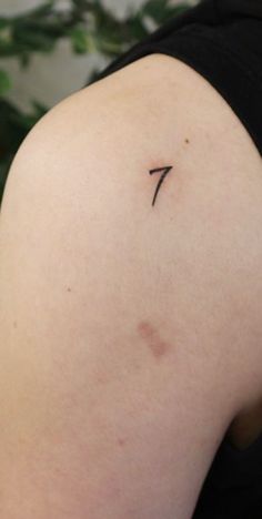 the back of a woman's shoulder with a small cross tattoo on her left arm