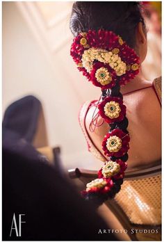 a woman wearing a red and white head piece with flowers in it's hair