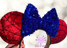 someone is holding up two red and blue minnie mouse ears with sequins on them