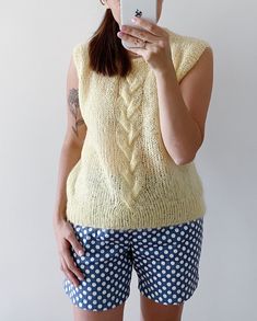 a woman taking a selfie in front of a white wall with polka dot shorts