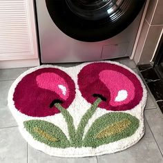 a pink flower rug sitting on top of a tile floor next to a dryer