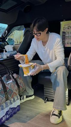 a woman sitting in the back seat of a car eating food from a paper plate