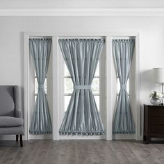 a living room filled with furniture and two windows covered in blue curtained drapes