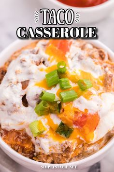 taco casserole in a white bowl topped with sour cream and green onions