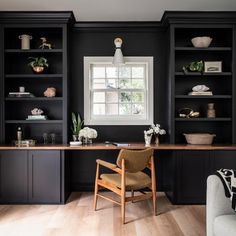 an office with black bookcases and wooden flooring is pictured in this image