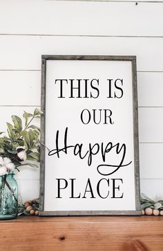 this is our happy place sign sitting on top of a shelf next to some flowers