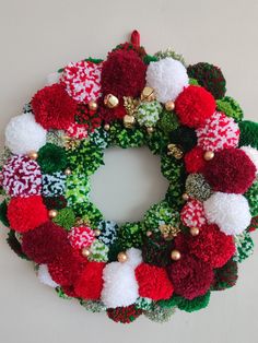 a christmas wreath with red, white and green pom - poms on it