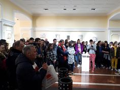 a group of people standing around each other in front of a room full of people