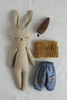 a stuffed animal next to a knitted hat and other items on a white sheet