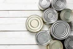 several cans of canned food on a white wooden table top view from above with copy space