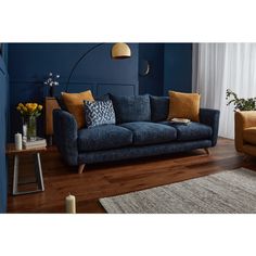 a living room with blue walls and wooden flooring, two chairs and a couch