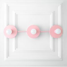 pink and white door knobs on the side of a door with two balls hanging from them