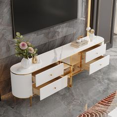 a white and gold sideboard with drawers in front of a large screen tv mounted on the wall