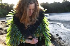 a woman standing on top of a beach covered in green and black strips with trees in the background