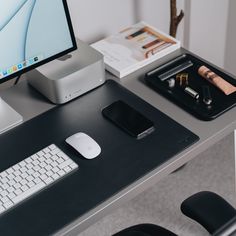 a desk with a keyboard, mouse and cell phone on it in front of a computer monitor