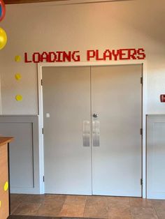 two white doors with the words loading players on them and balloons hanging from the ceiling