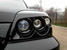 the front end of a black car with two lights on it's headlight