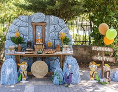 an outdoor dessert table set up for a birthday party with cartoon characters and balloons in the background