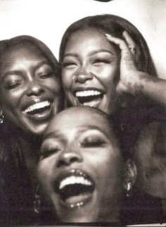 three women are laughing together in black and white