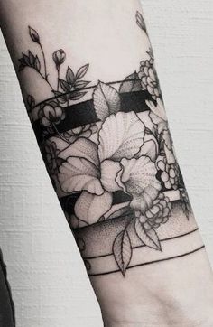 a woman's arm with flowers on it and a black ribbon around the wrist