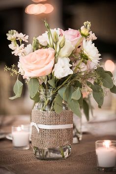 a vase filled with flowers sitting on top of a table next to two lit candles