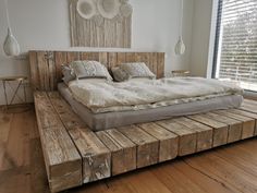 a bed made out of wooden planks in a room with windows and wood flooring