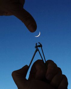 someone is holding something in their hand with the moon behind them