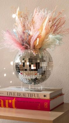 a mirrored disco ball sitting on top of two books and a pink flower in it