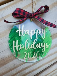 a glass ornament with the words happy holidays on it hanging from a string