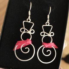 a pair of silver earrings with pink ribbon on them in a black gift box,