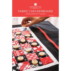 a person is making a checkerboard out of fabric and buttons on a table