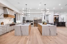 a large kitchen with an island in the middle and wooden flooring on the other side