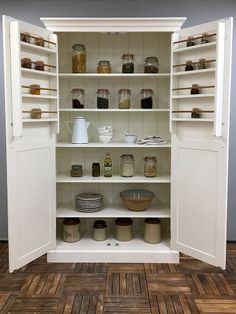 an open pantry with many jars and bowls on it's shelves in a room