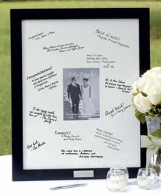 a table topped with a vase filled with white flowers and a framed photo on top of it