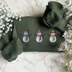 three snowmen on green sweater with white flowers