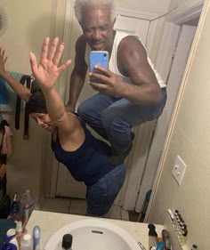 an older man taking a selfie in front of a mirror with his hands up