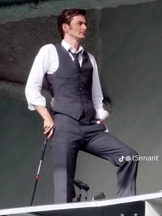 a man in a suit and tie standing on top of a boat with a cane