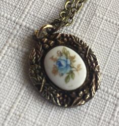 Painted Blue Flower Oval Pendant set in a Bronze floral mount, pendant measures .75" tall, and comes on a 18" chain. Please take a look at my storefront at: https://www.etsy.com/shop/FabFinds42?ref=seller-platform-mcnav I have a wide selection of one-of-a-kind items, from clothing and toys to home decor and gift items, and I add new things almost every day. Vintage Flower-shaped Nickel-free Necklaces, Vintage Blue Flower Pendant Necklace, Blue Floral Print Jewelry For Gift, Vintage Blue Jewelry With Flower Charm, Vintage Blue Flower Pendant Jewelry, Blue Nickel-free Flower Pendant Necklace, Blue Flower Pendant Necklace Nickel Free, Blue Vintage Charm Necklace As Gift, Blue Floral Print Flower-shaped Jewelry