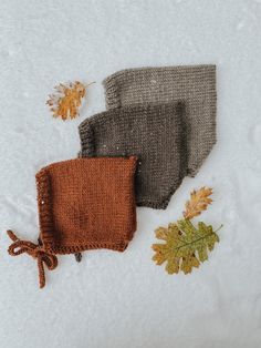 three pieces of knitted cloth with autumn leaves on the side and one piece of yarn next to it