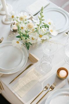 a table set with plates, silverware and flowers