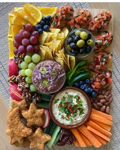 a platter filled with fruit, crackers, dips and other food items