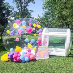 an inflatable bubble ball with colorful balloons is on the grass next to it