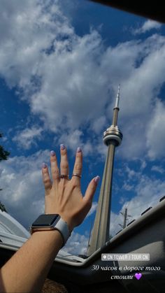 a person's hand reaching up into the sky with a tower in the background