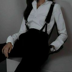 a woman in white shirt and black suspenders posing for the camera with her hands on her hips